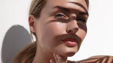 Imagem fechada no rosto de uma mulher. Ele tem a pele bronzeada e o cabelo loiro. O rosto está exposto aos efeitos da poluição e da radiação na pele.